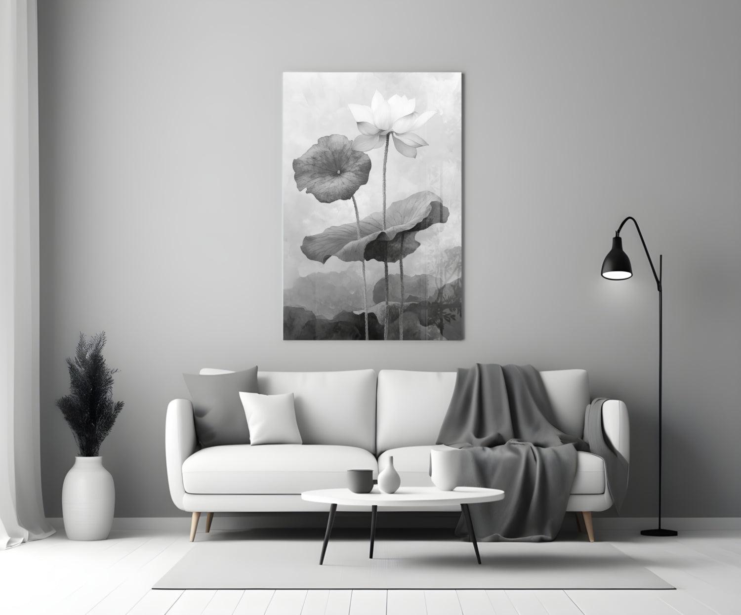 Black and white glass wall art depicting water lilies displayed above a white sofa in a minimalist living room setting.