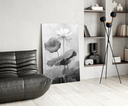 Black and white water lily glass art leaning against white wall in minimalist living room with leather chair and shelving.
