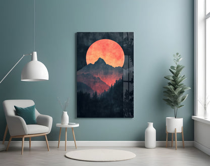 Red Moon Rising glass wall art depicting an orange sun behind dark forested mountains, displayed in a minimalist room setting.