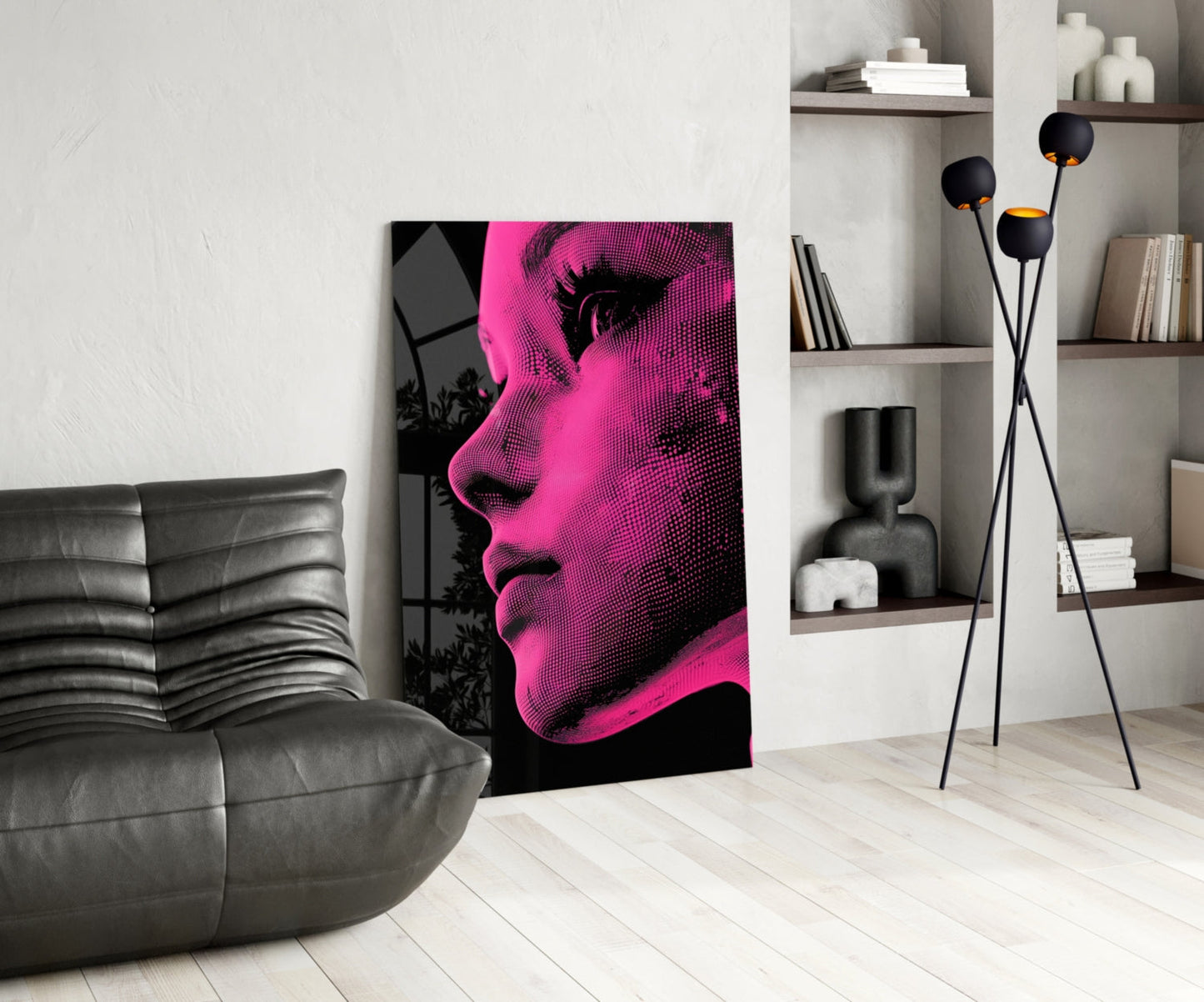 Modern living room interior featuring pink and black halftone portrait art leaning against white wall beside gray leather sofa.