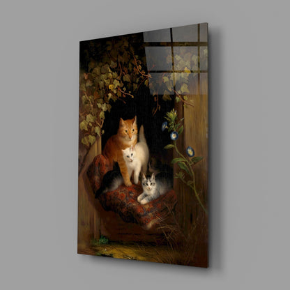 Angled view of glass wall art depicting an orange and white cat with two kittens on a wooden surface, surrounded by autumn foliage and flowering vines against a dark background.