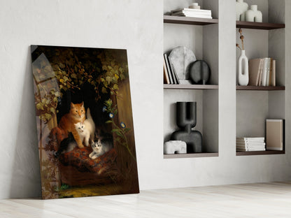 Glass wall art leaning against white wall displays three cats among golden foliage and flowers against dark background.