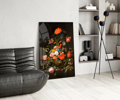 Modern living room interior featuring a vibrant floral still-life glass wall art depicting orange and pink flowers against a dark background, displayed next to a black leather chair and white shelving unit.