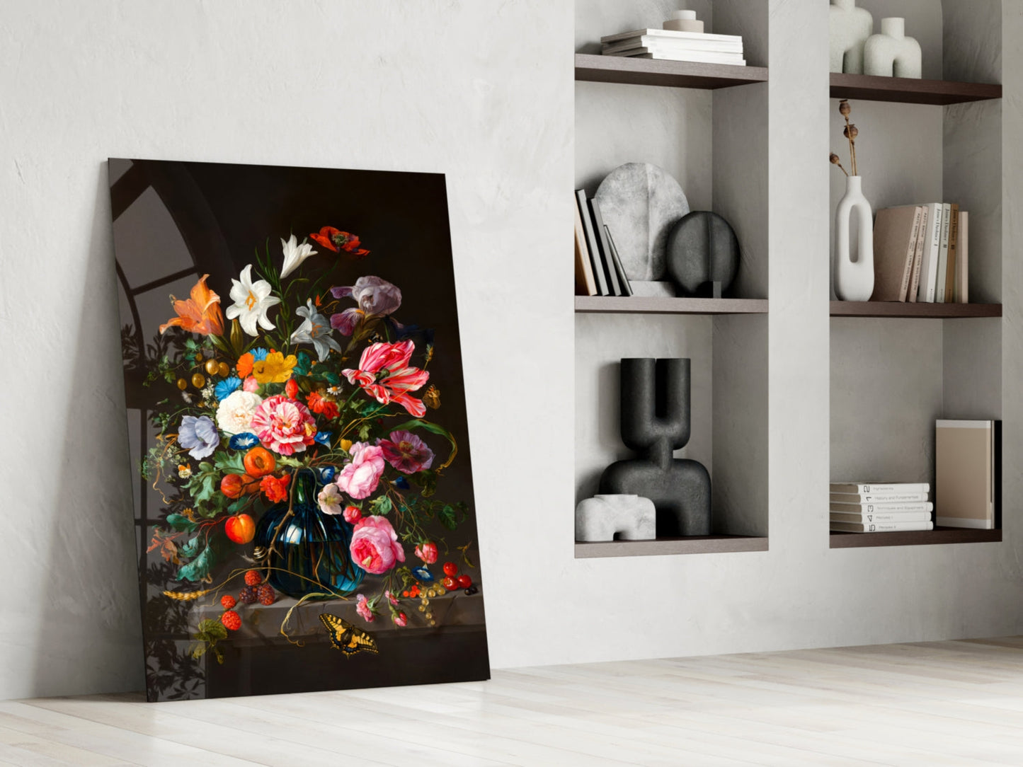 Classical floral still life glass art leaning against white wall beside built-in shelving with decorative objects.
