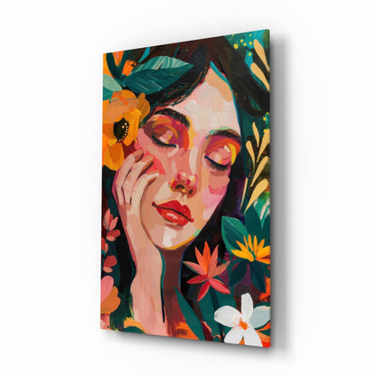 Angled perspective of colorful glass wall art featuring a woman's face surrounded by vibrant orange, red, and yellow flowers on dark background.