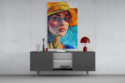 Colorful abstract portrait of woman wearing orange hat displayed above modern gray media console with red lamp and decorative objects.
