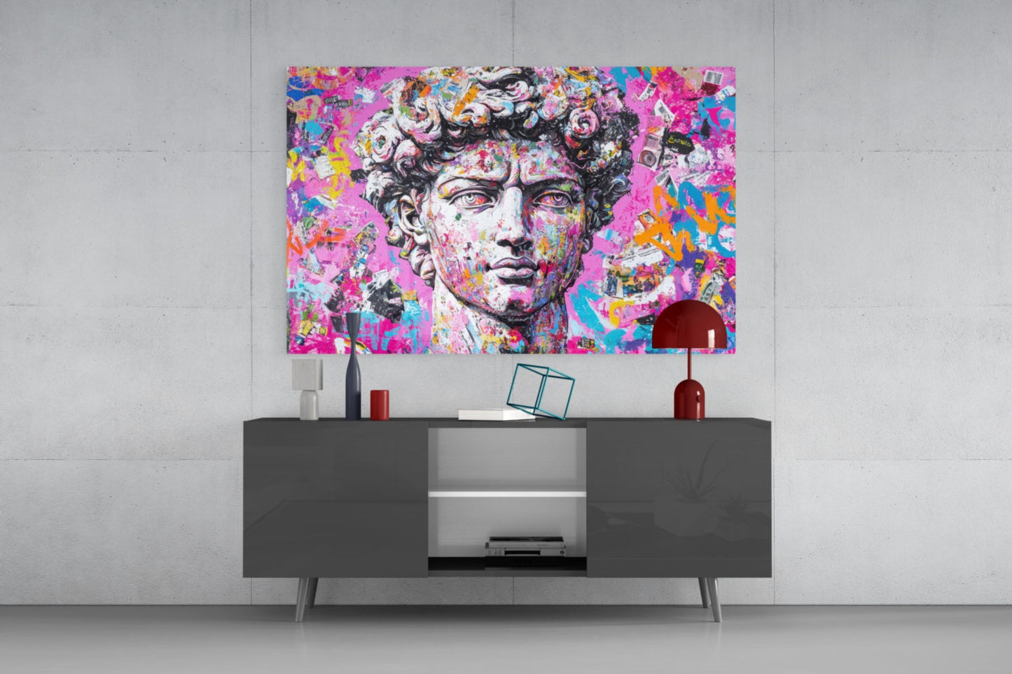 Vibrant pop art glass wall panel featuring classical bust with neon pink, blue, and yellow graffiti-style overlay, displayed above dark console table in modern interior.