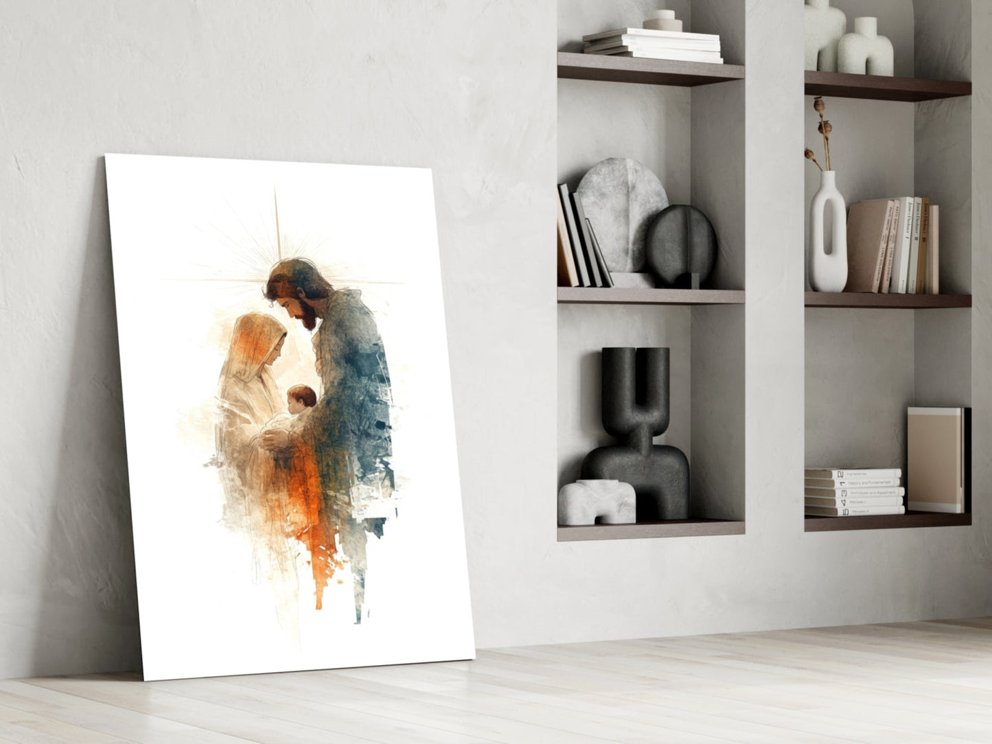 White glass panel leaning against wall depicting watercolor Holy Family figures in warm orange and blue tones, displayed beside built-in shelving.
