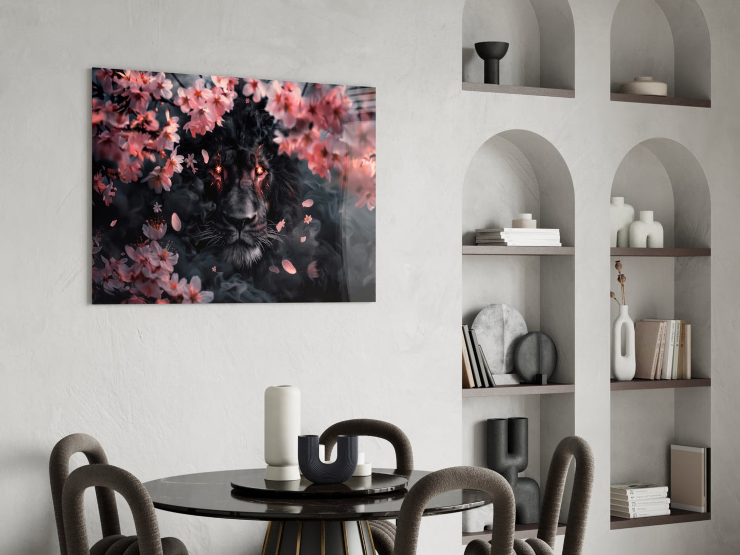 Black lion portrait surrounded by pink flowers displayed on white wall above round black dining table with gray chairs.