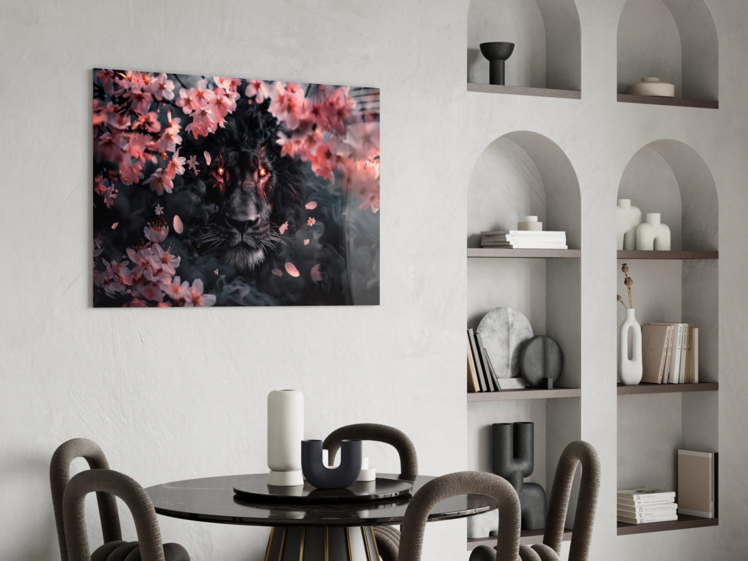 Black lion portrait surrounded by pink flowers displayed on white wall above round black dining table with gray chairs.