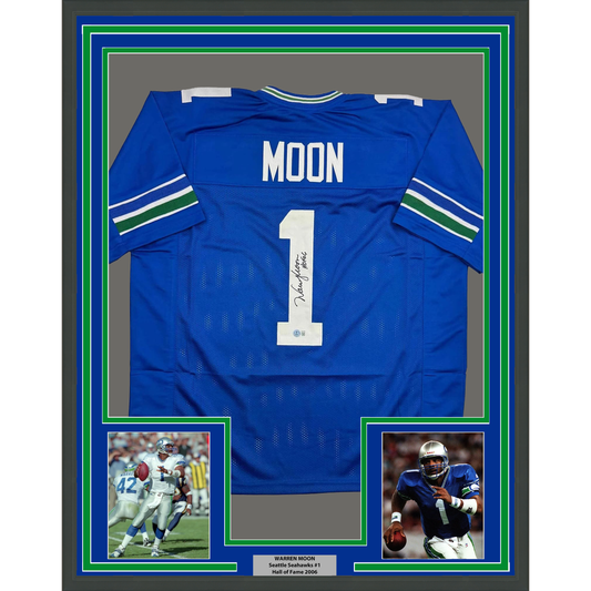 Framed blue Seattle Seahawks jersey number 1 signed by Warren Moon, displayed with two action photos below and green matting border.