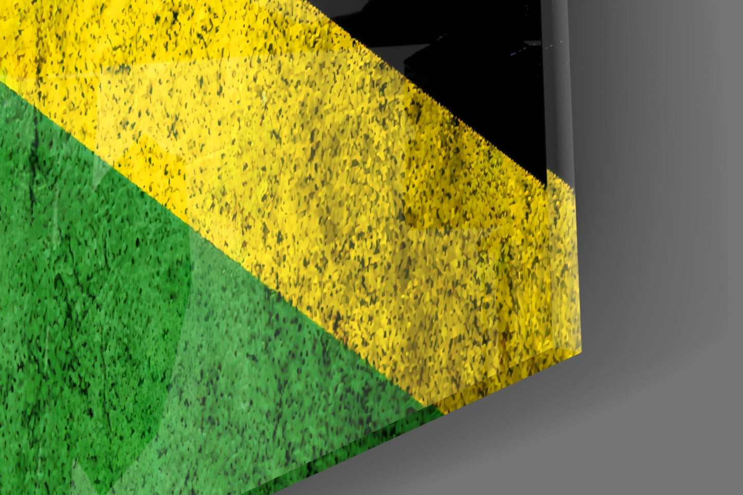 Close-up angled view of Jamaica flag glass wall art showing green and yellow textured glass panels with black diagonal stripe detail.