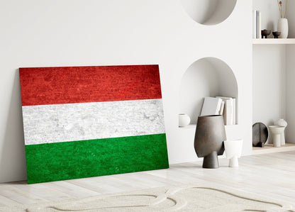 Hungarian flag glass wall art leaning against white wall in minimalist interior with decorative objects.
