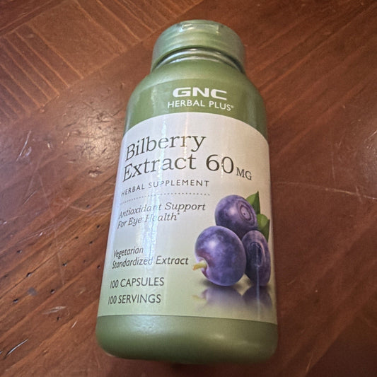 GNC Herbal Plus Bilberry Extract 60mg bottle with green cap and cream label featuring purple bilberries, resting on a wooden surface.