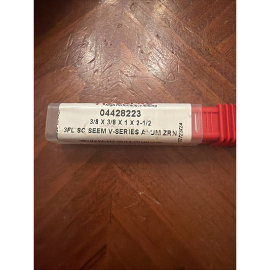 White and red carbide end mill package labeled 04428223 lying on brown wood surface, showing product specifications and branding.