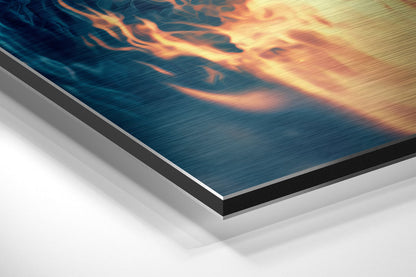 Angled view of brushed aluminum Dibond wall art showing layered edge construction with fiery orange and blue abstract imagery on surface.