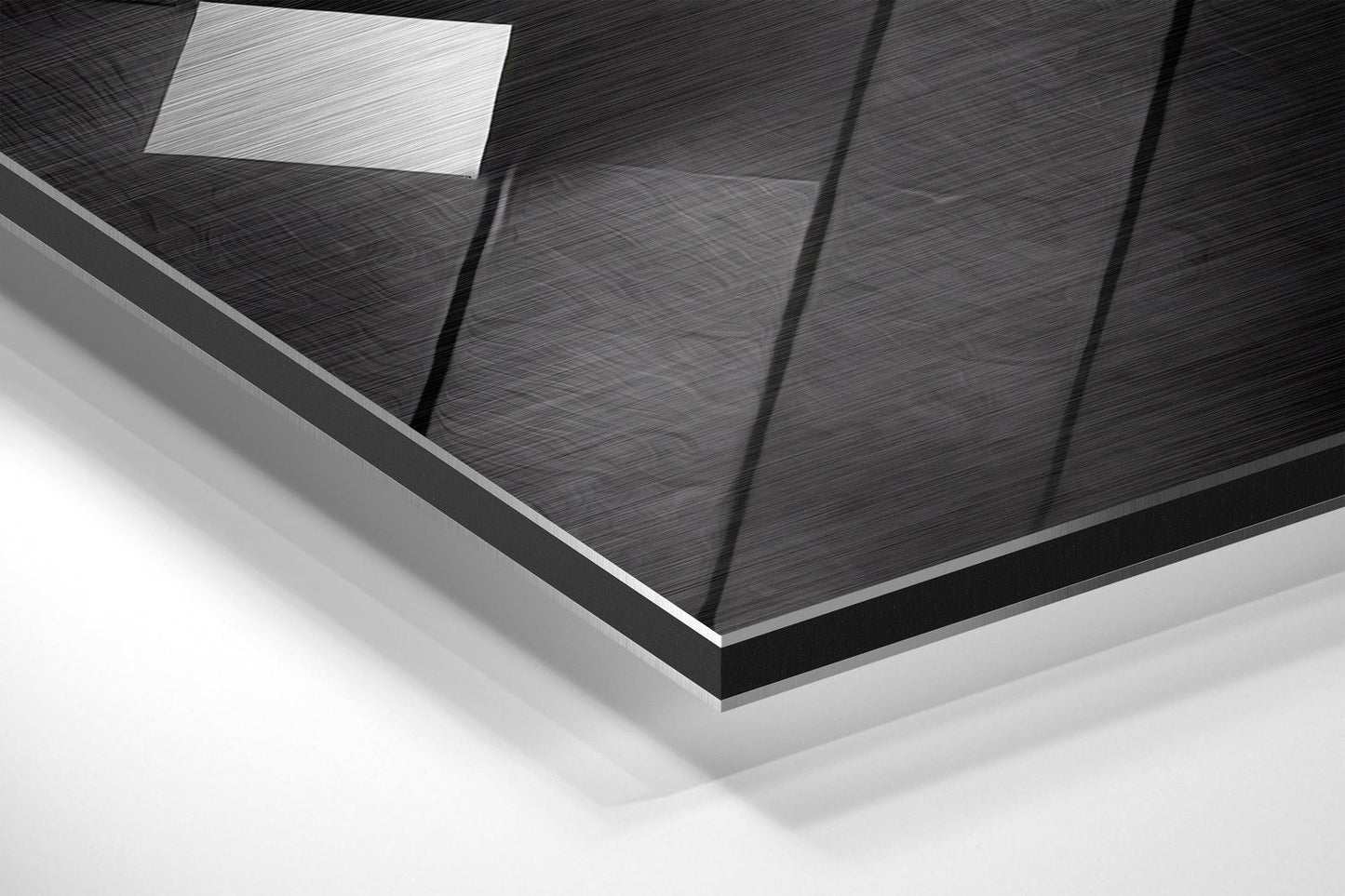 Close-up angled view of brushed aluminum Dibond wall art showing textured black surface with vertical panel divisions and white ceiling light reflection.