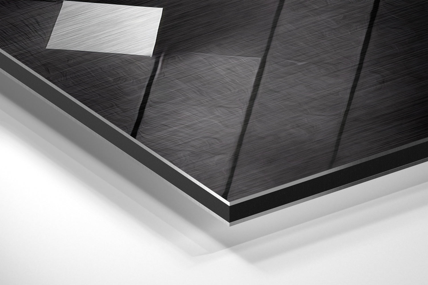 Close-up angled view of brushed aluminum Dibond wall art showing textured black surface with vertical panel divisions and white ceiling light reflection.