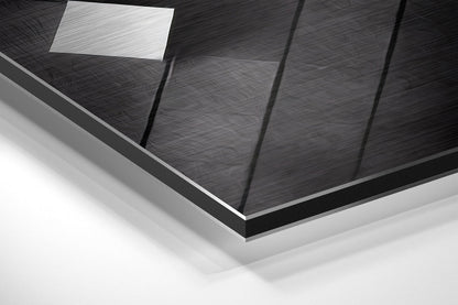 Close-up angled view of brushed aluminum Dibond wall art showing textured black surface with vertical panel divisions and white ceiling light reflection.