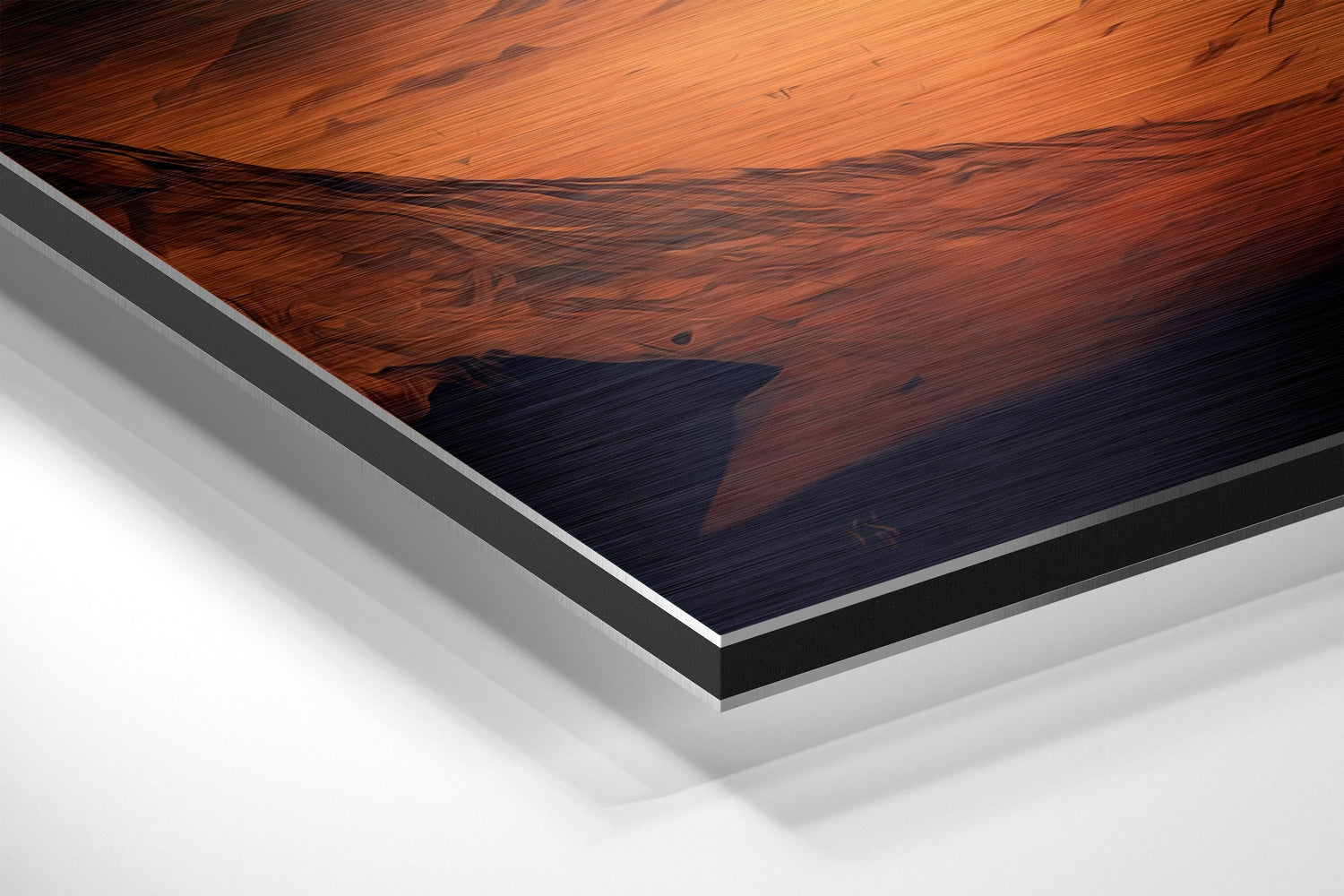 Close-up angled view of brushed aluminum Dibond layered panel showing wood grain texture with orange and dark blue tones.