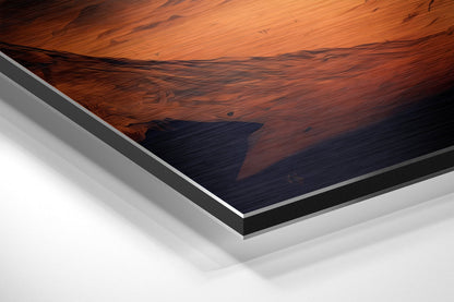 Close-up angled view of brushed aluminum Dibond layered panel showing wood grain texture with orange and dark blue tones.