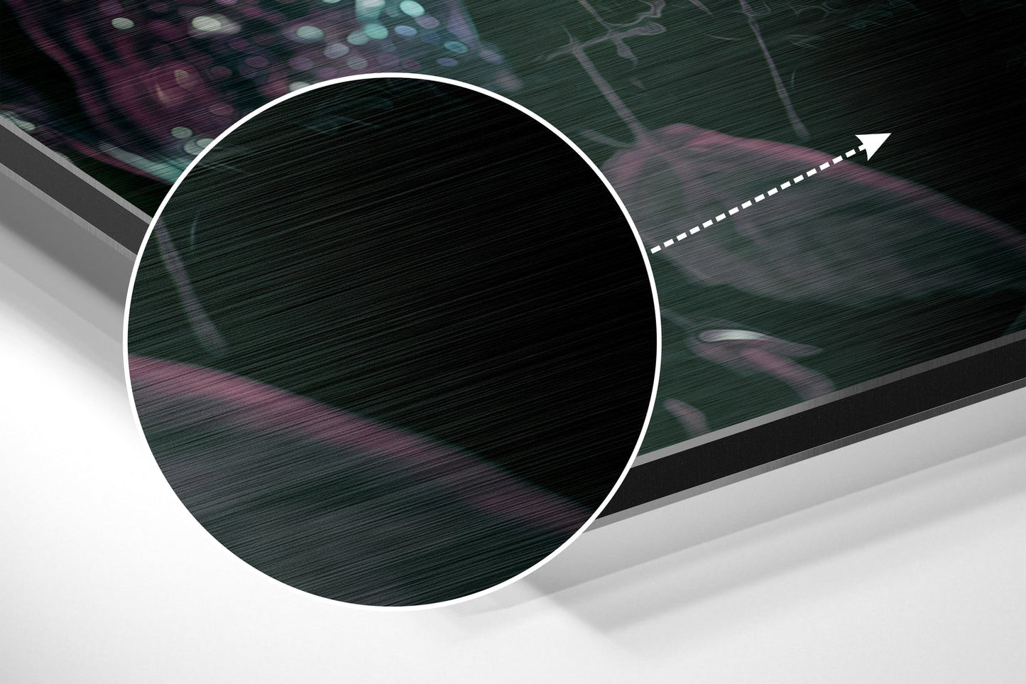 Close-up angled view of brushed aluminum wall art with white circular frame and directional arrow against blurred green and pink background.