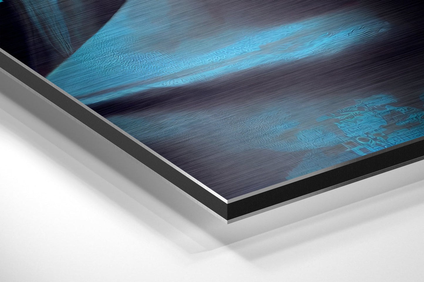 Close-up angled view of brushed aluminum Dibond wall art showing layered edges with blue and dark tones against white background.