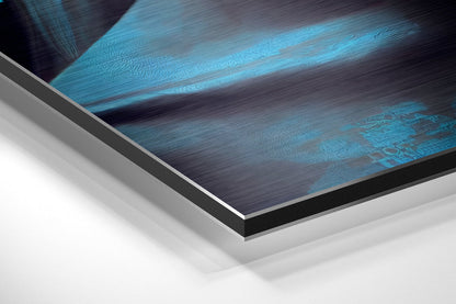 Close-up angled view of brushed aluminum Dibond wall art showing layered edges with blue and dark tones against white background.