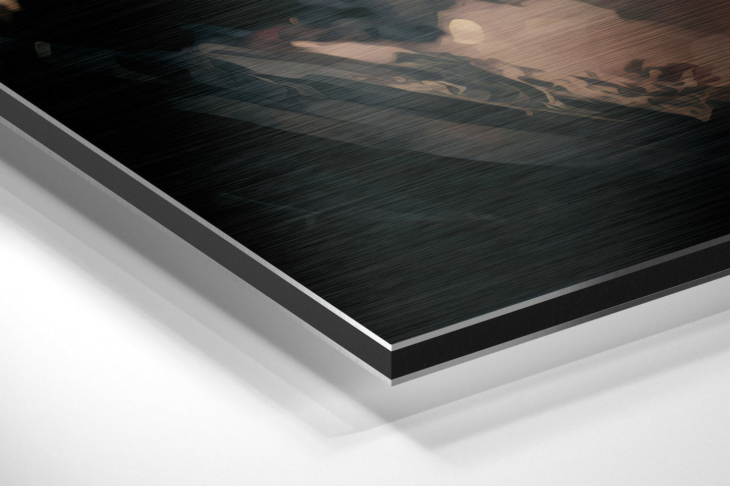 Close-up angled view of layered Dibond panel showing brushed black aluminum surface with white backing material visible at edge.