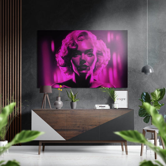 Pink neon portrait artwork displayed above a wood and white dresser in a modern interior setting with plants and pendant lighting.