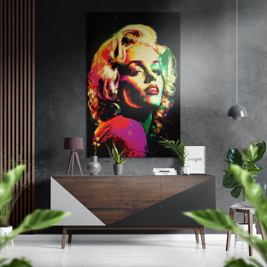 Vibrant neon pop art portrait with yellow, red, green, and purple tones displayed above a wood and white dresser in a modern interior setting.