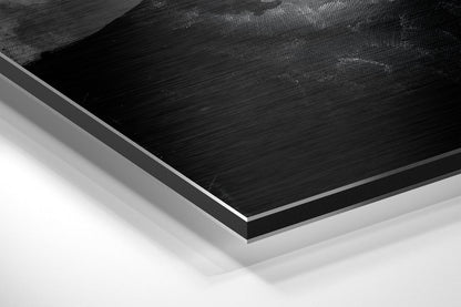 Close-up angled view of layered Dibond panel showing brushed black aluminum surface with white and gray backing layers.