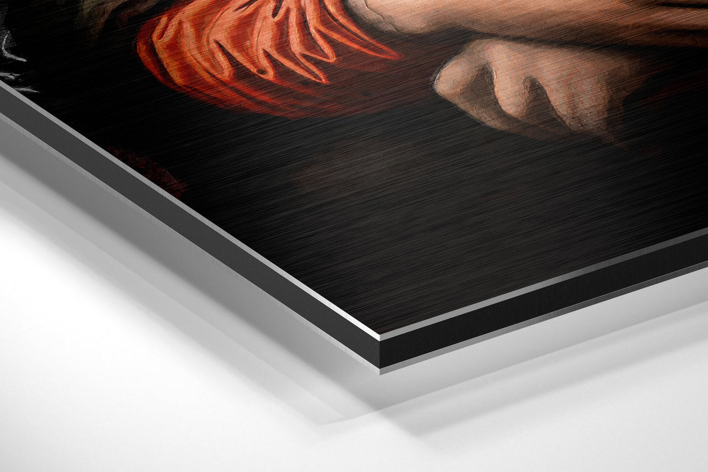 Close-up angled view of brushed aluminum Dibond wall art showing layered edges and metallic finish with portrait detail visible at top.