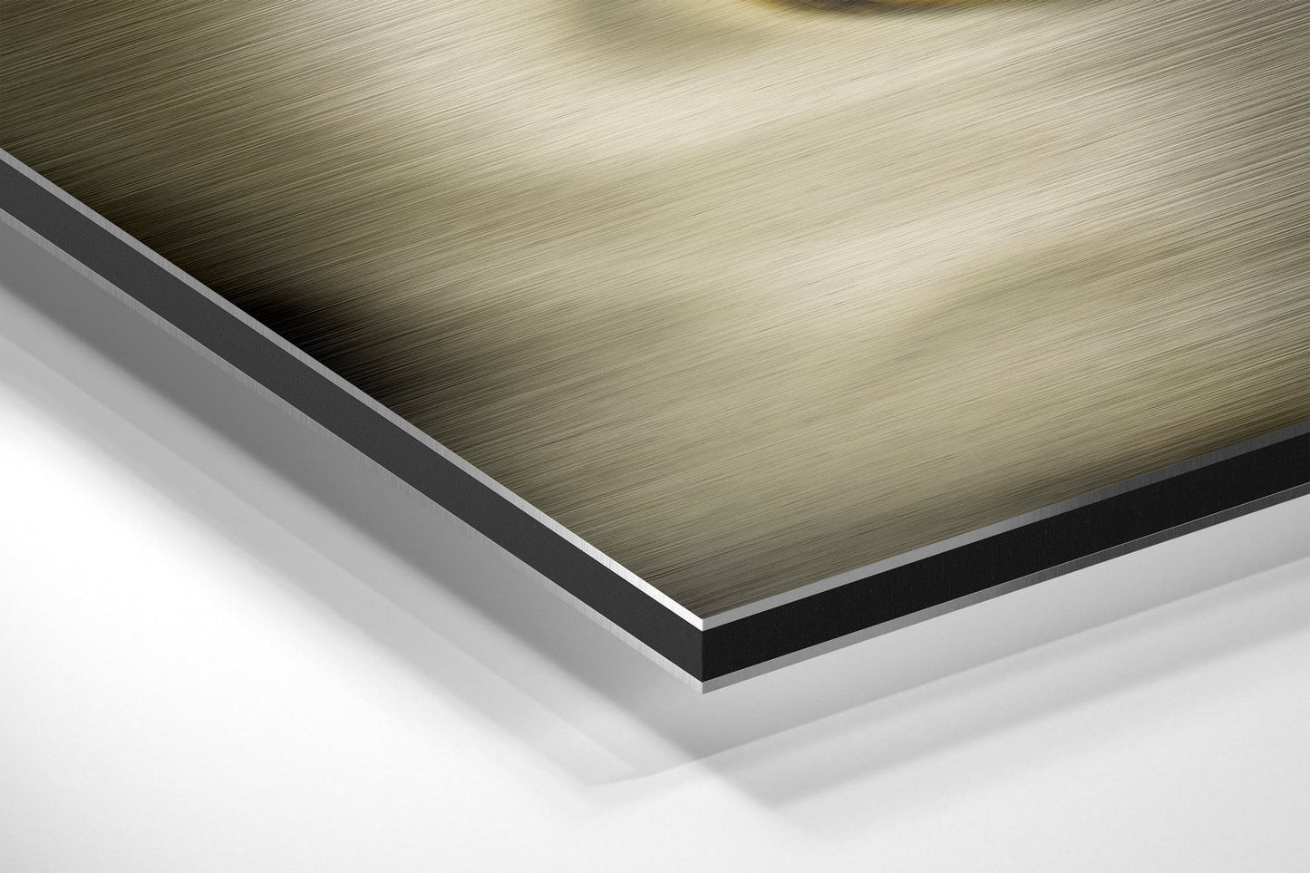 Close-up angled view of layered Dibond panel showing brushed metallic gold top surface with black and white composite layers visible at beveled edge.