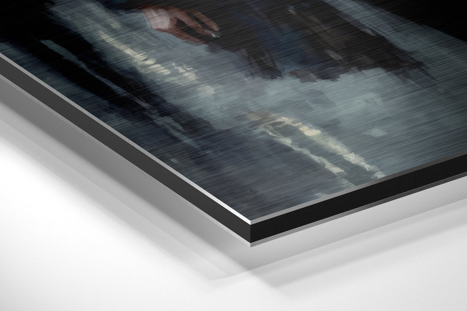 Close-up angled view of brushed aluminum Dibond panel layers showing metallic surface texture and white backing material.