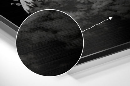 Close-up angled view of brushed aluminum Dibond wall art showing circular black textured center with white border and directional arrow detail.