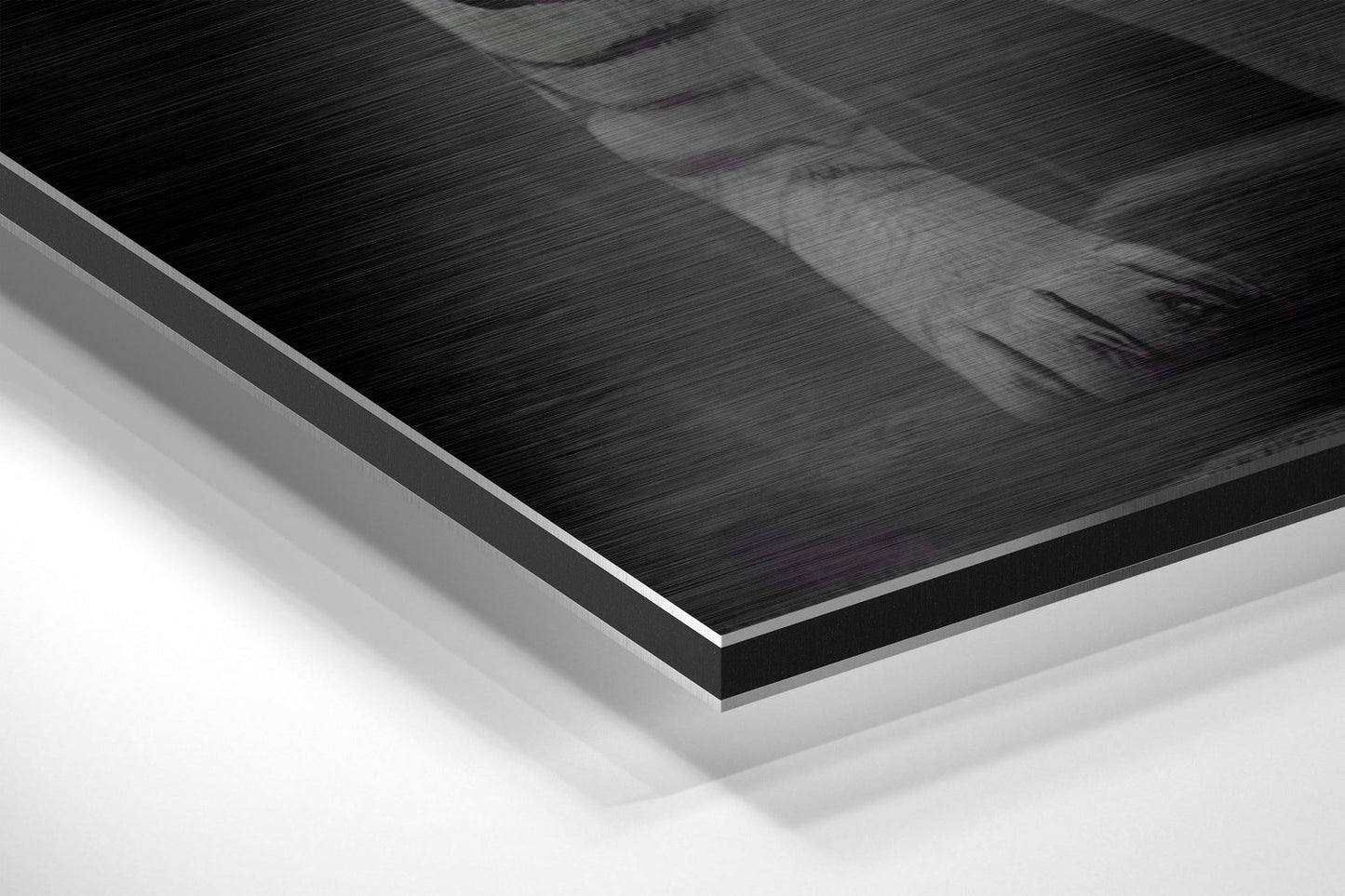 Close-up angled view of layered Dibond panel showing brushed black aluminum surface with white backing layers and silver edge trim.