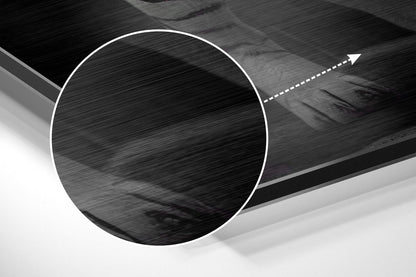 Close-up detail of brushed aluminum surface with circular cutout and directional arrow indicator on dark abstract wall art.