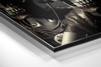 Angled perspective view of brushed aluminum Dibond wall art featuring dark sculptural skulls with metallic highlights and beveled edge framing.