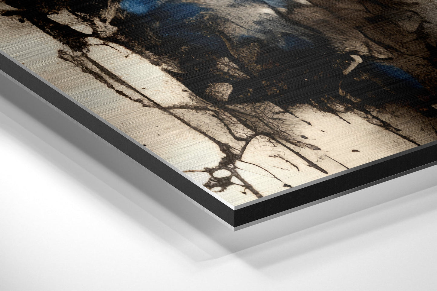 Close-up angled view of brushed aluminum Dibond wall art with black frame edge, showing tree branch shadows on light wood surface.