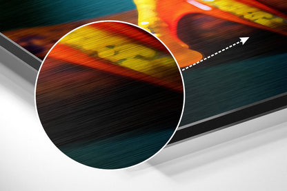 Close-up angled view of brushed aluminum wall art showing vibrant red, yellow, and teal gradient with directional arrow detail.