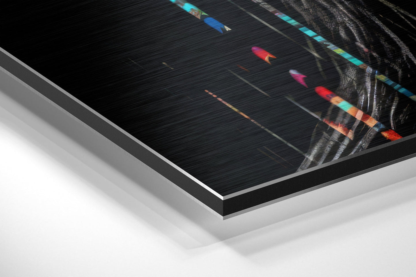 Angled perspective shot of brushed aluminum dibond art print showing colorful abstract lines and figure on dark textured background with silver edge detail.