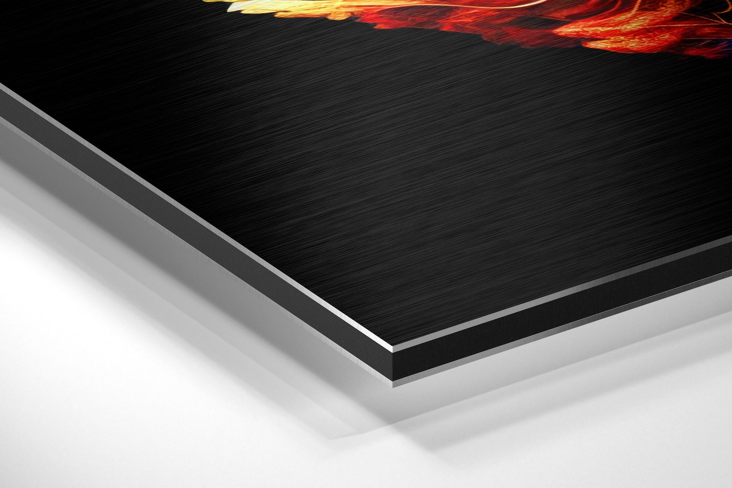 Angled perspective view of layered Dibond wall art showing brushed black aluminum surface with white backing and gold-red flame detail at top edge.