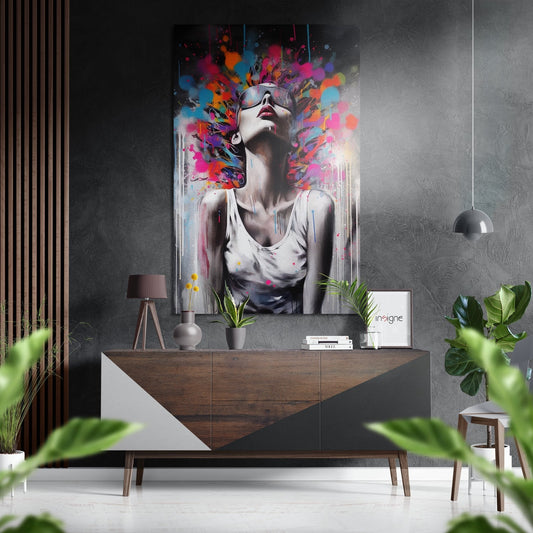 Modern interior with colorful abstract portrait art displayed above wooden dresser with plants and pendant lighting.