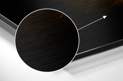 Angled view of brushed black aluminum circular wall art with white border and directional arrow on dark background.