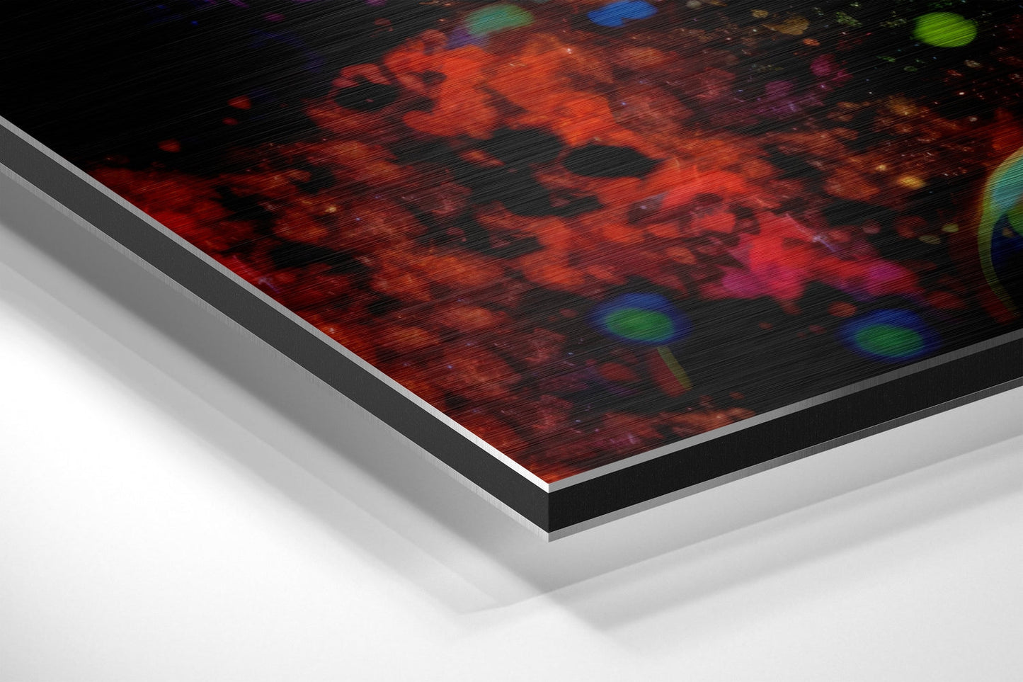 Angled product shot of brushed aluminum Dibond wall art with red and orange abstract imagery and colorful accents, showing layered frame edge detail.
