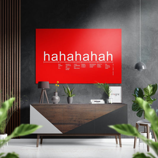 Red aluminum wall art displaying "hahaha" text with a laughter intensity scale below, mounted in modern interior above wooden dresser.