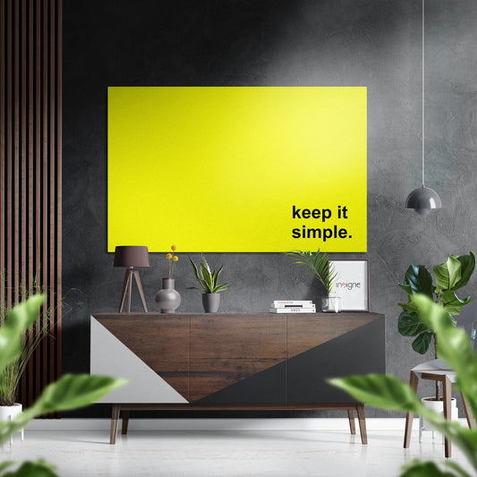 Bright yellow aluminum wall art with "keep it simple." text displayed above a wooden credenza in a modern living room setting.