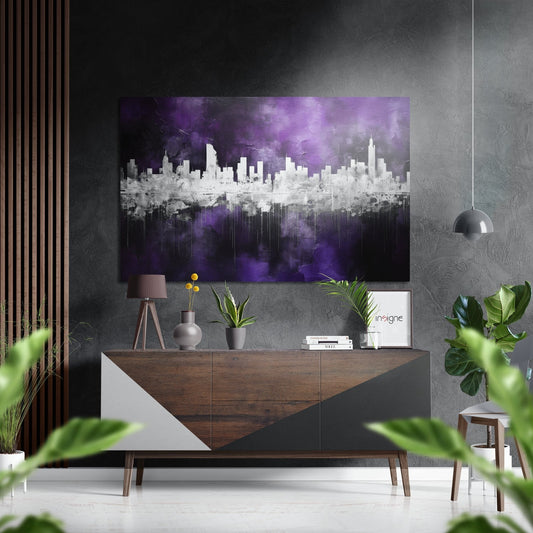 Purple and white cityscape wall art displayed above a wooden console table in a modern interior with plants and pendant lighting.