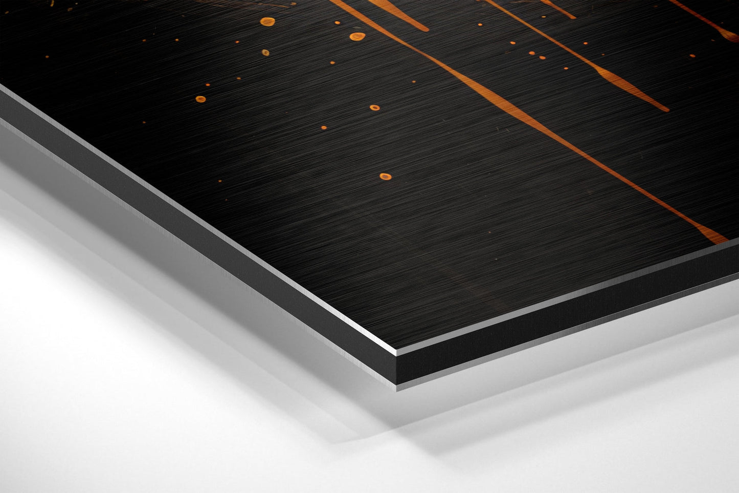 Close-up angled view of layered Dibond wall art showing black brushed surface with orange geometric lines and white backing layers.